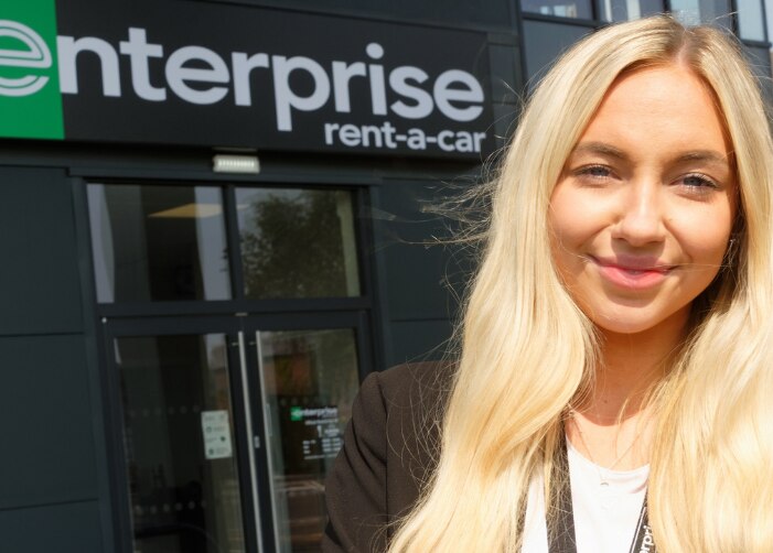 Selfie of female worker in front of Enterprise sign