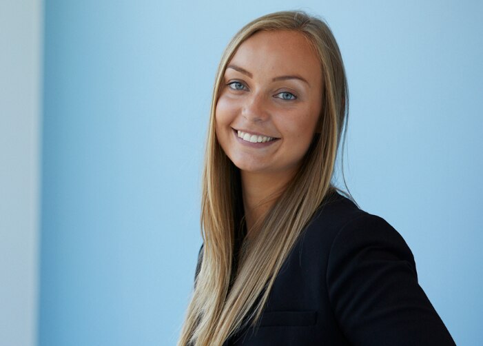 Female employee sitting in front of a blue wall