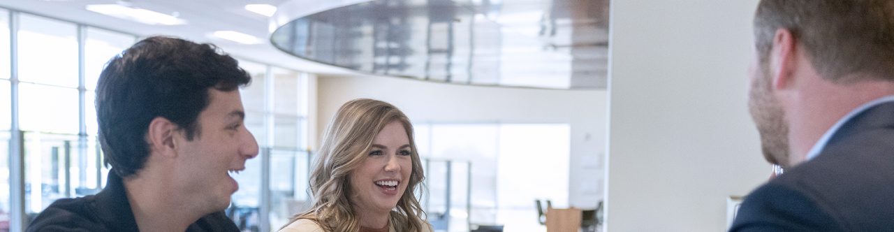 Two Enterprise Mobility team members talk with others over a desk. 