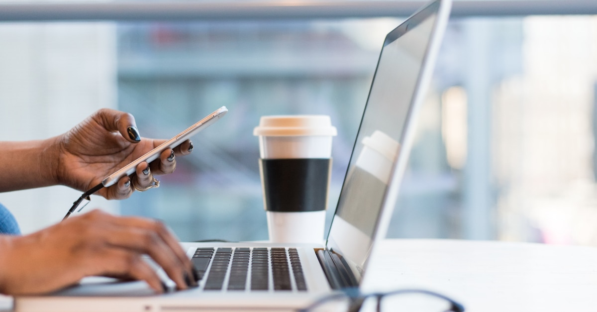 Sostener un teléfono y escribir un MacBook en una cafetería