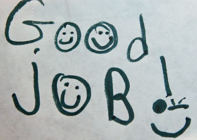 Pieza de papel de cuaderno que dice "buen trabajo" con caras sonrientes