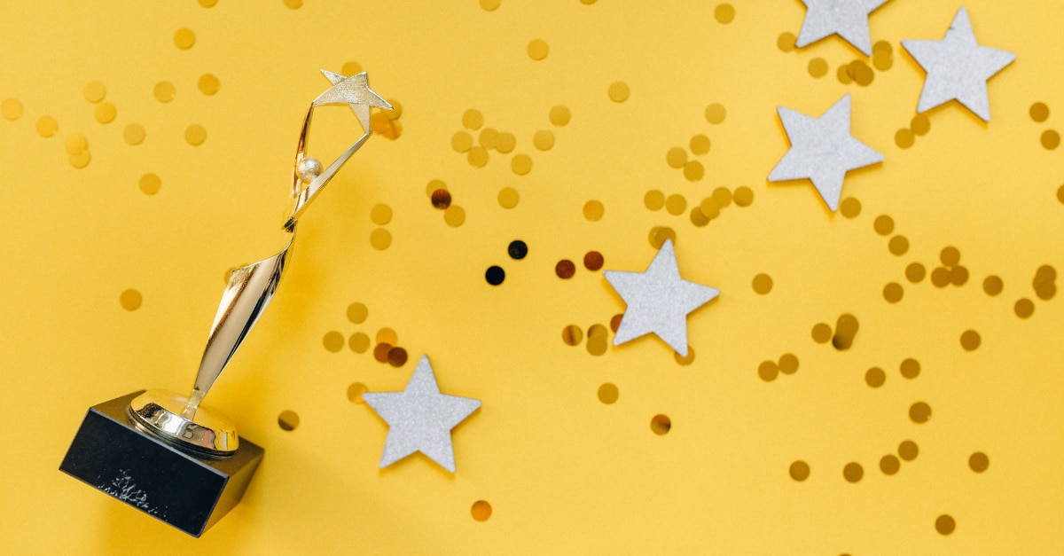 Trofeo con brillo y estrellas esparcidas sobre un fondo amarillo
