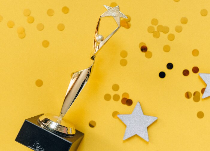 Trofeo con brillo y estrellas esparcidas sobre un fondo amarillo