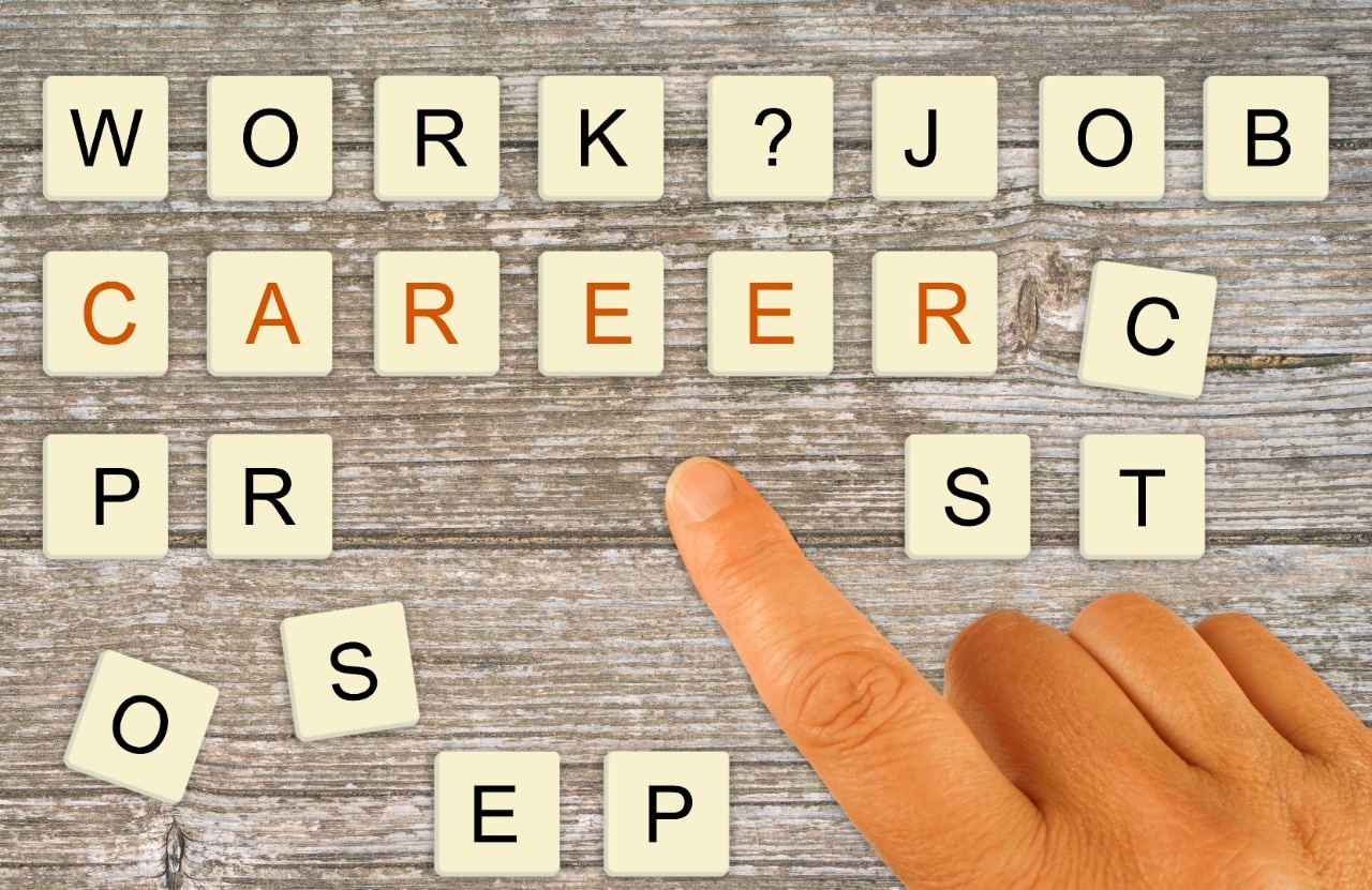 Las fichas de letras están ordenadas por un dedo para deletrear "trabajo", "trabajo", "carrera" y luego las fichas adicionales dispersas