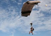 Gente a punto de aterrizar en la playa después de practicar paracaidismo