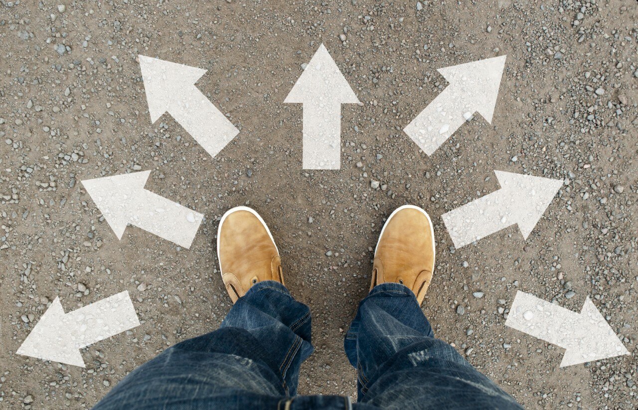 Pies sobre el pavimento rodeado de flechas que apuntan a diferentes direcciones