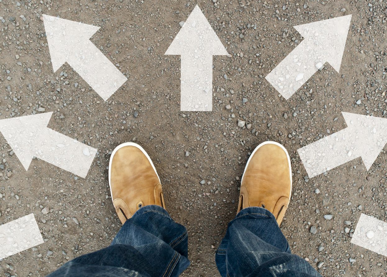 Pies sobre el pavimento rodeado de flechas que apuntan a diferentes direcciones