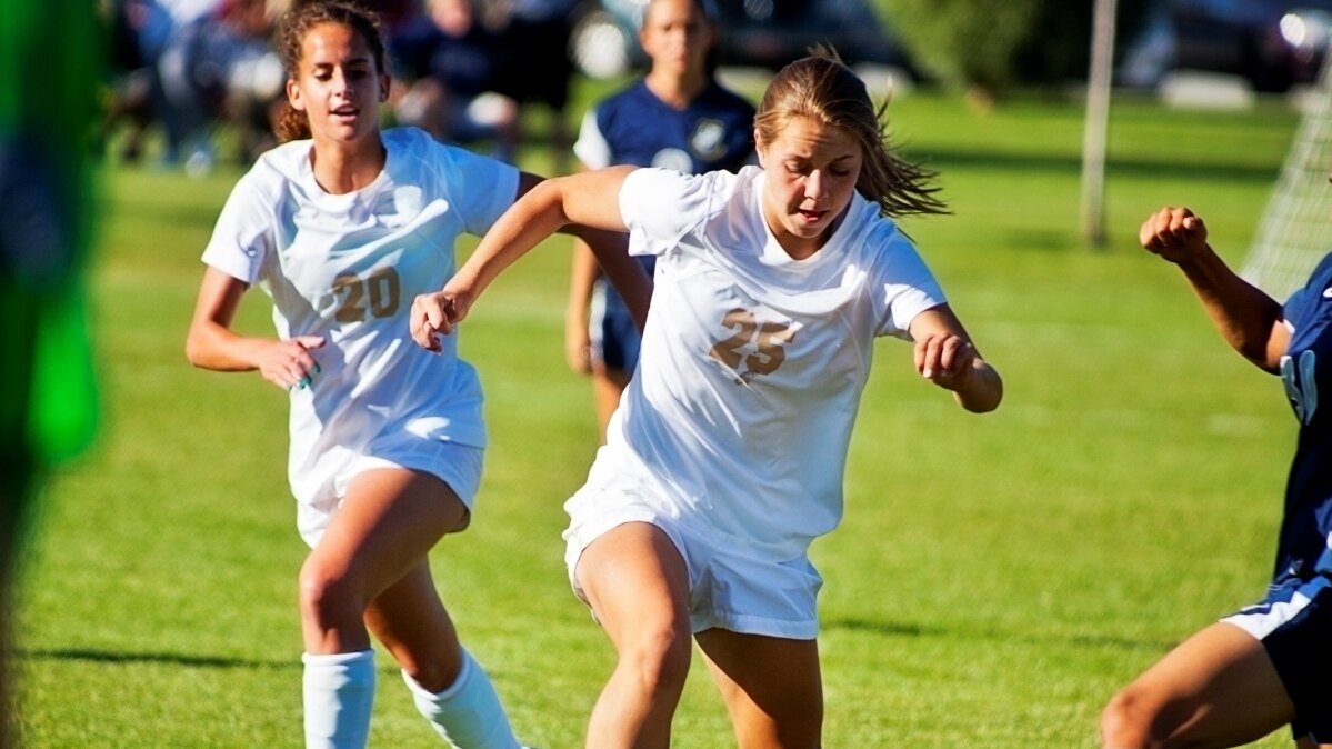 Chicas jugando al fútbol con uniformes blancos
