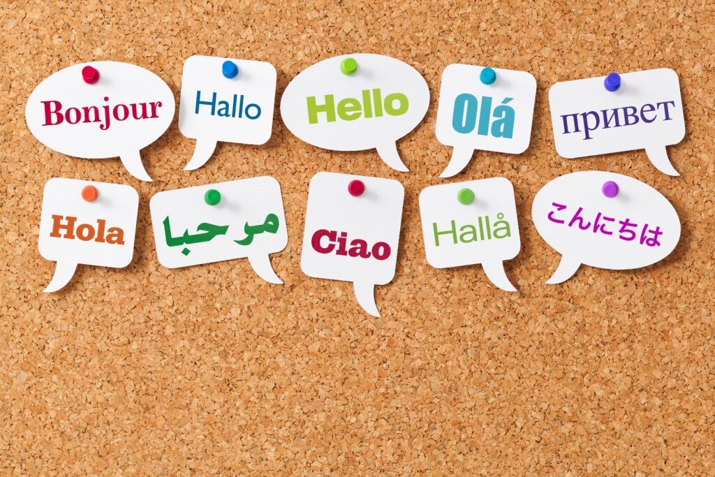La palabra "Hola" en diferentes idiomas en las burbujas de palabras fijadas a un tablero de corcho