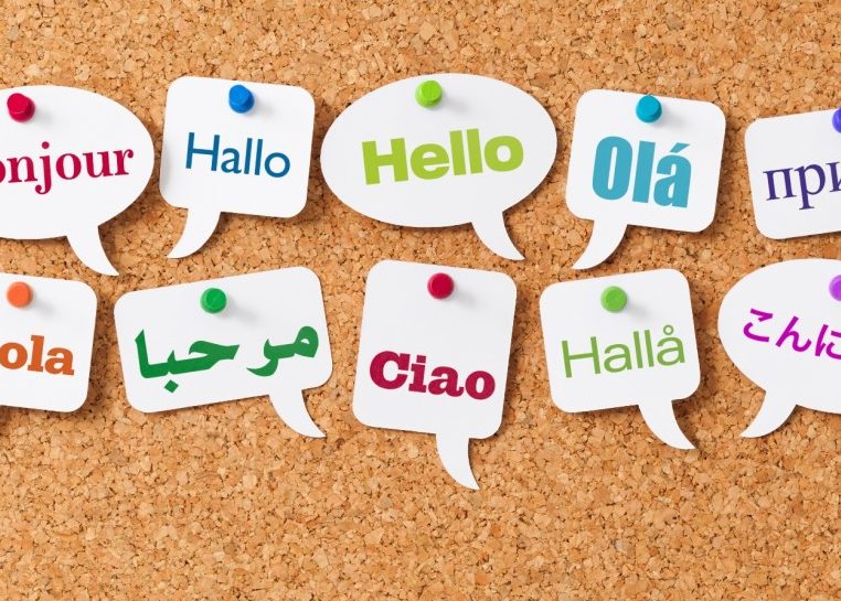La palabra "Hola" en diferentes idiomas en las burbujas de palabras fijadas a un tablero de corcho