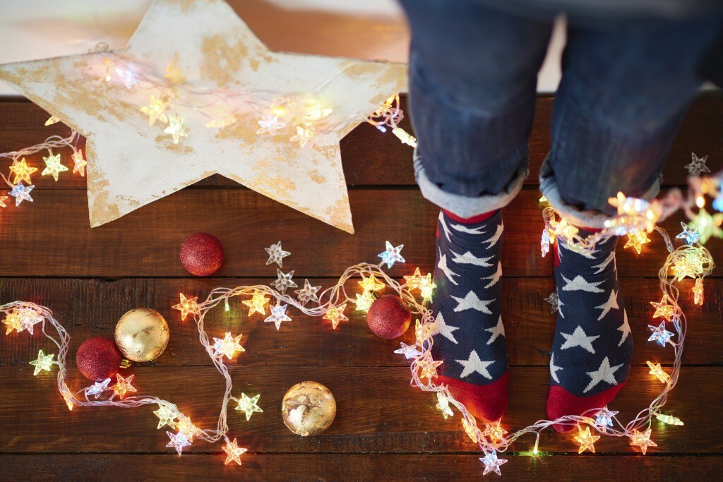 Pies en calcetines de estrellas rodeados de luces y adornos para Navidad
