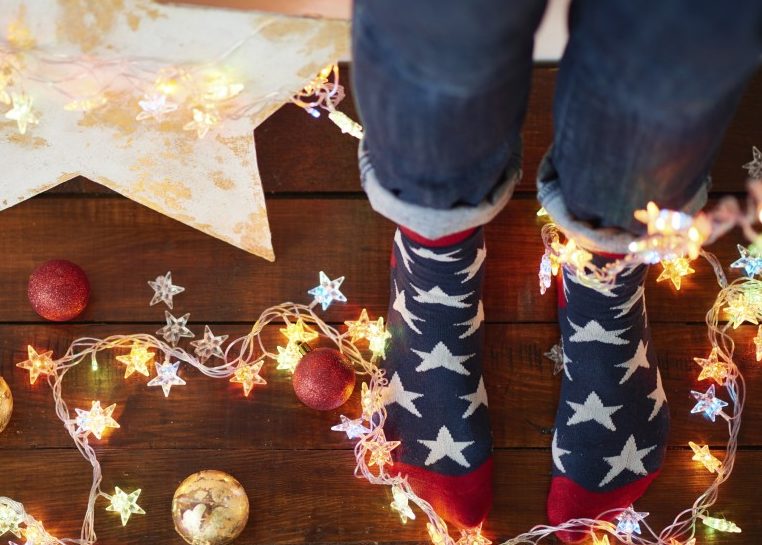 Pies en calcetines de estrellas rodeados de luces y adornos para Navidad