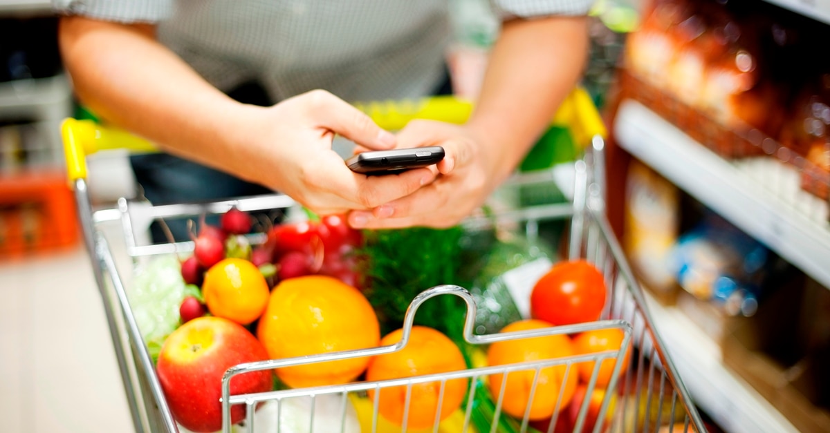 Enviar mensajes de texto mientras empuja el carrito de compras lleno de frutas y verduras