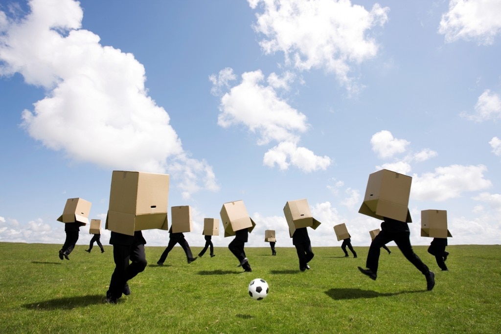 Gente jugando al fútbol con cajas de cartón sobre sus cabezas