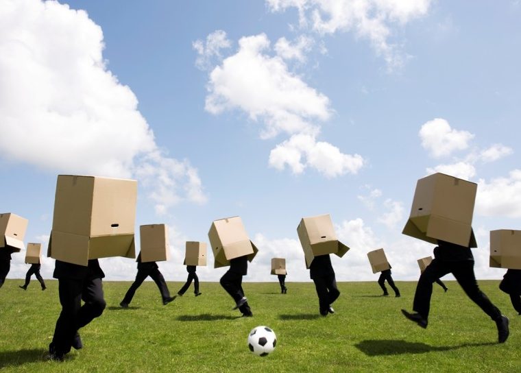 Gente jugando al fútbol con cajas de cartón sobre sus cabezas