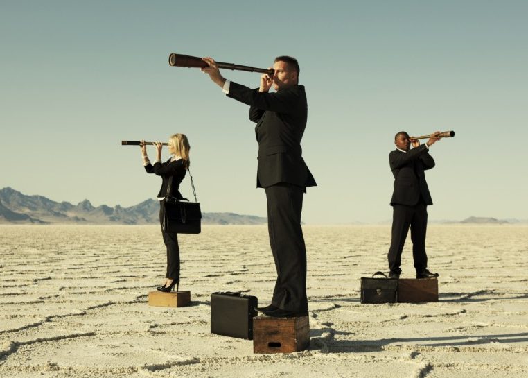 Personas en trajes con telescopios de pie en cajas en un desierto