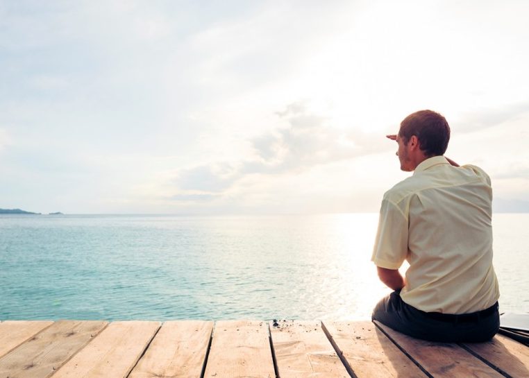 Hombre sentado en la terraza con vistas al océano