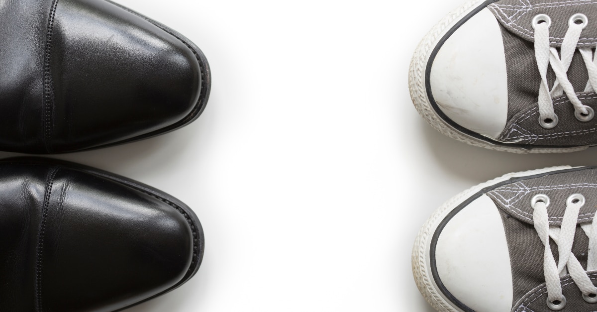 Par de zapatos de vestir negros frente a un par de converse gris