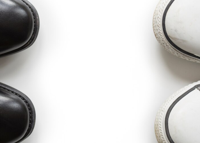 Par de zapatos de vestir negros frente a un par de converse gris