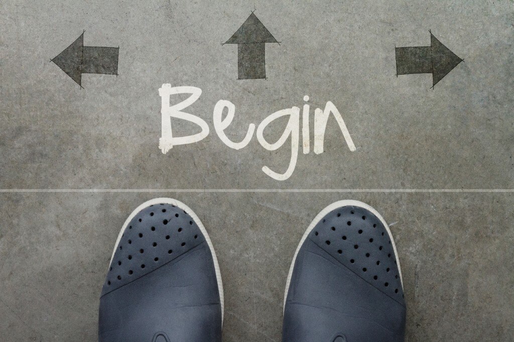 Pies en el suelo con "Begin" escrito rodeado de flechas