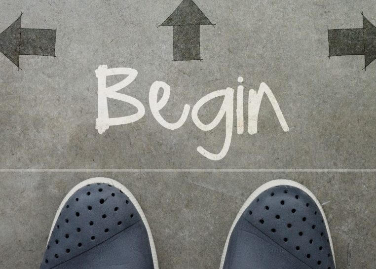 Pies en el suelo con "Begin" escrito rodeado de flechas