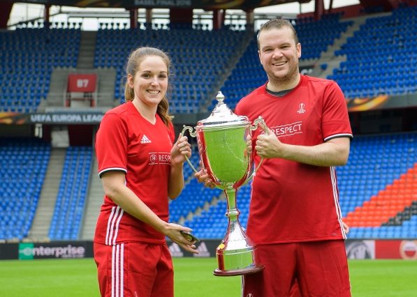 Dos jugadores en uniforme con un trofeo