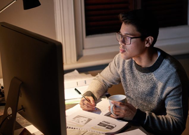 Estudiante revisando un documento tarde por la noche en el brillo de la pantalla de una computadora