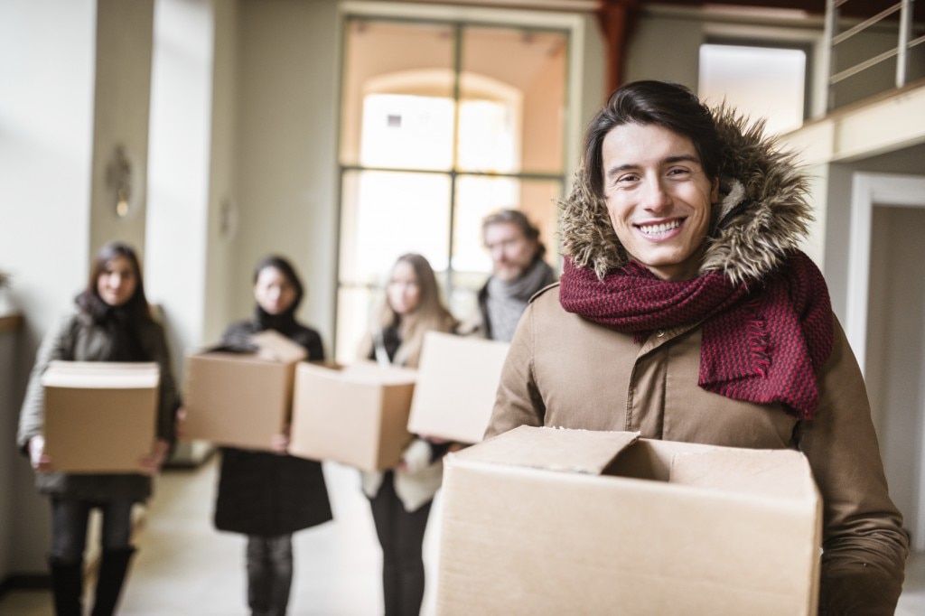 Personas en abrigos que transportan cajas