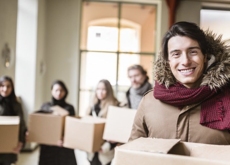 Personas en abrigos que transportan cajas