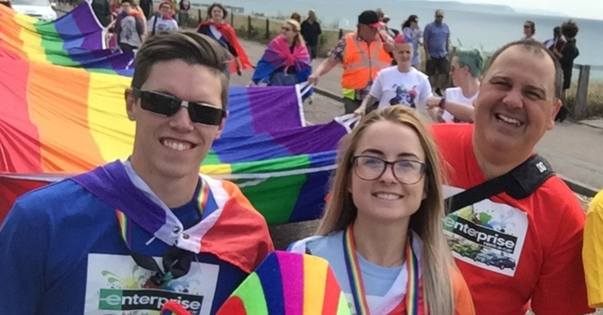 Luke y otros empleados de Enterprise con la gran bandera DEL ORGULLO en un desfile