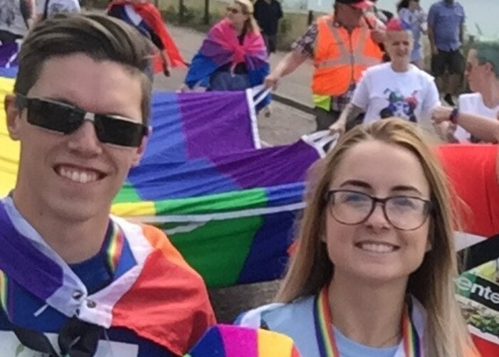 Luke y otros empleados de Enterprise con la gran bandera DEL ORGULLO en un desfile