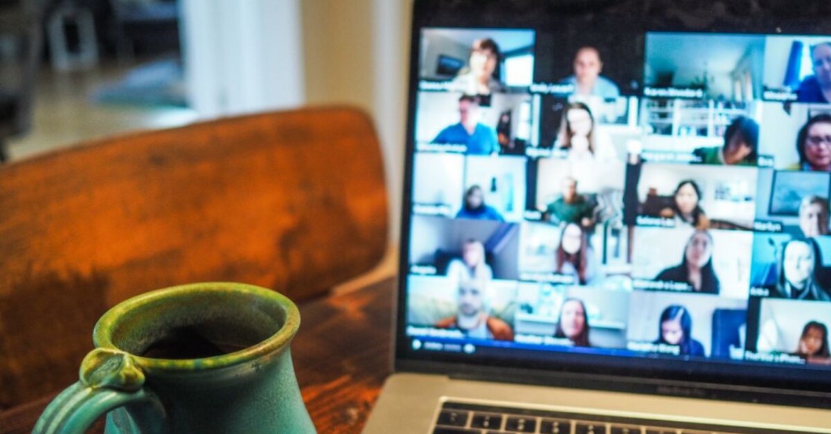 MacBook con Zoom para reuniones abiertas y una taza de café sentada en la mesa