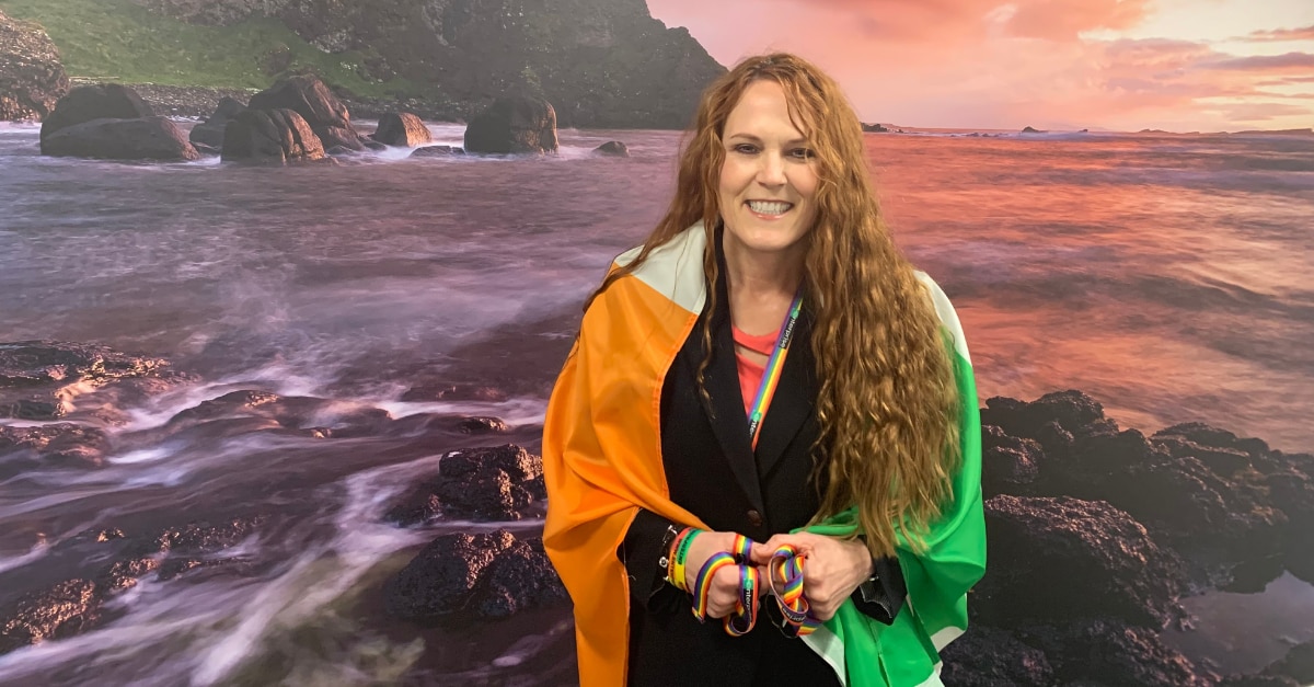 Leslee con bandera irlandesa alrededor de sus hombros frente al océano