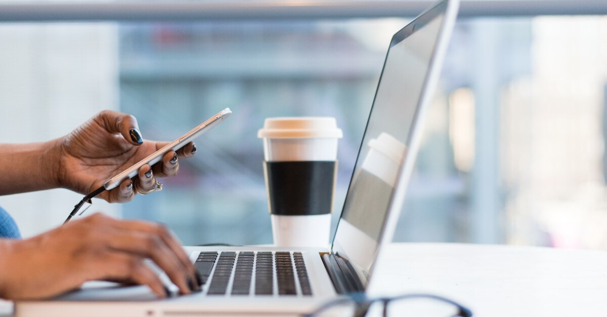 Sostener un teléfono y escribir un MacBook en una cafetería