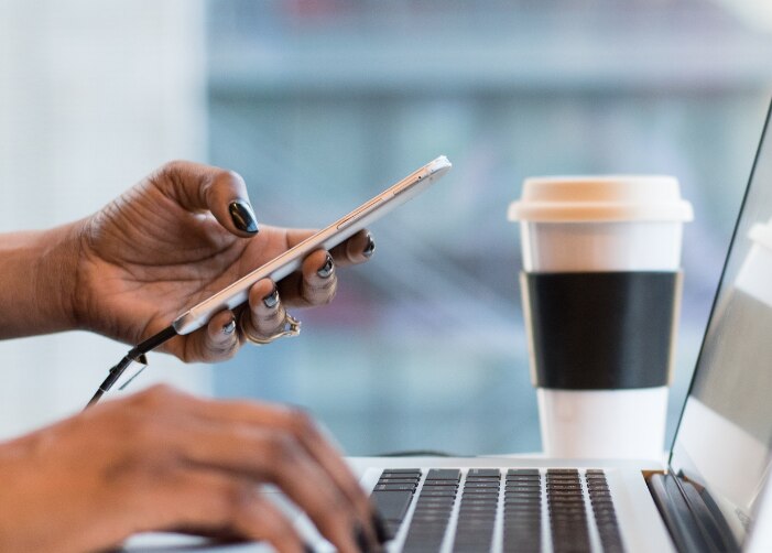 Sostener un teléfono y escribir un MacBook en una cafetería