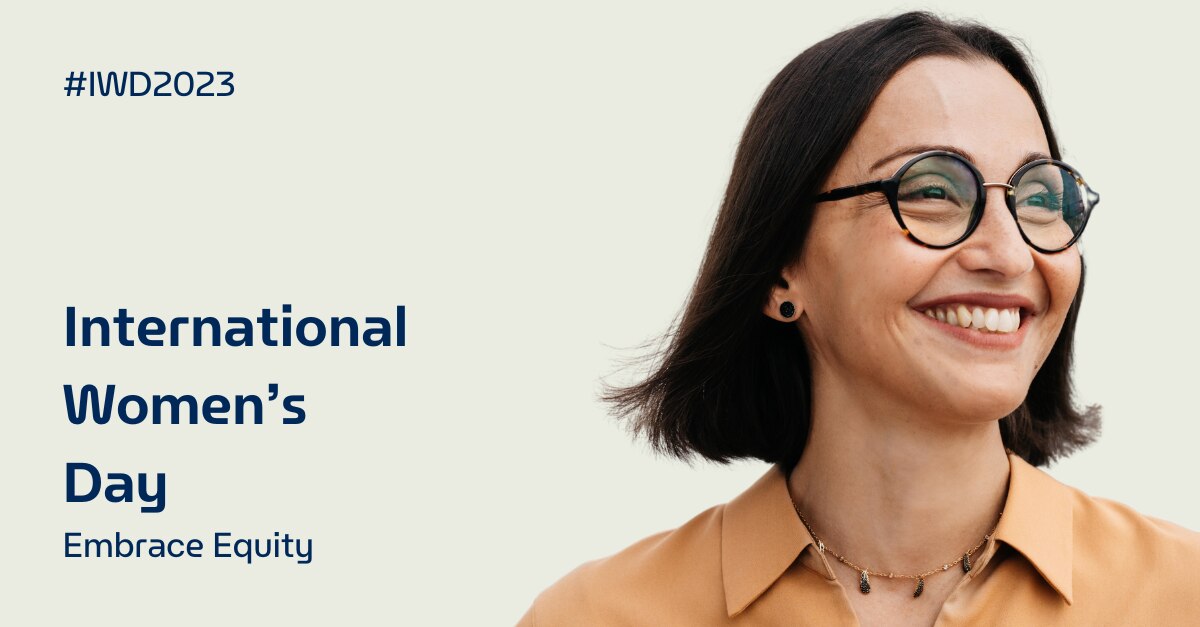 Mujer sonriendo con "Día Internacional de la Mujer Abrace Equity" escrito en el fondo
