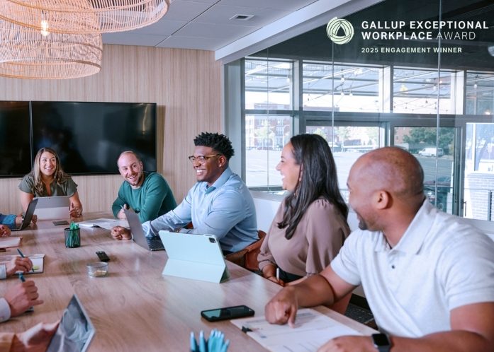 Enterprise mobility team members in workplace sitting around a table talking with Gallup Exceptional Workplace award logo..