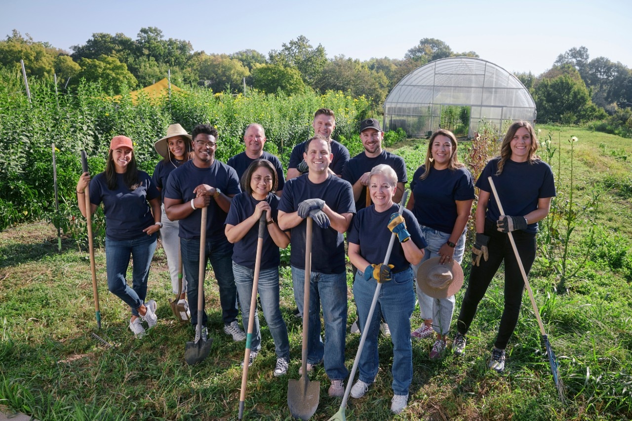 Un grupo de sonrientes integrantes del equipo de Enterprise Mobility con palas y rastrillos en un campo soleado