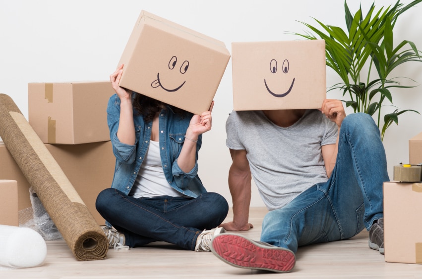 dos personas sentadas en el suelo con cajas de cartón con caras sonrientes dibujadas sobre la cabeza de la gente
